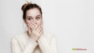 Ein junges Mädchen mit großen Augen bedeckte ihren Mund mit den Händen und sah erschrocken zur Seite. Nahansicht. Credit: Canva