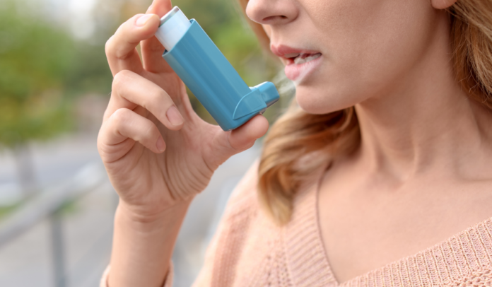 Frau inhaliert mit blauem Inhalator
